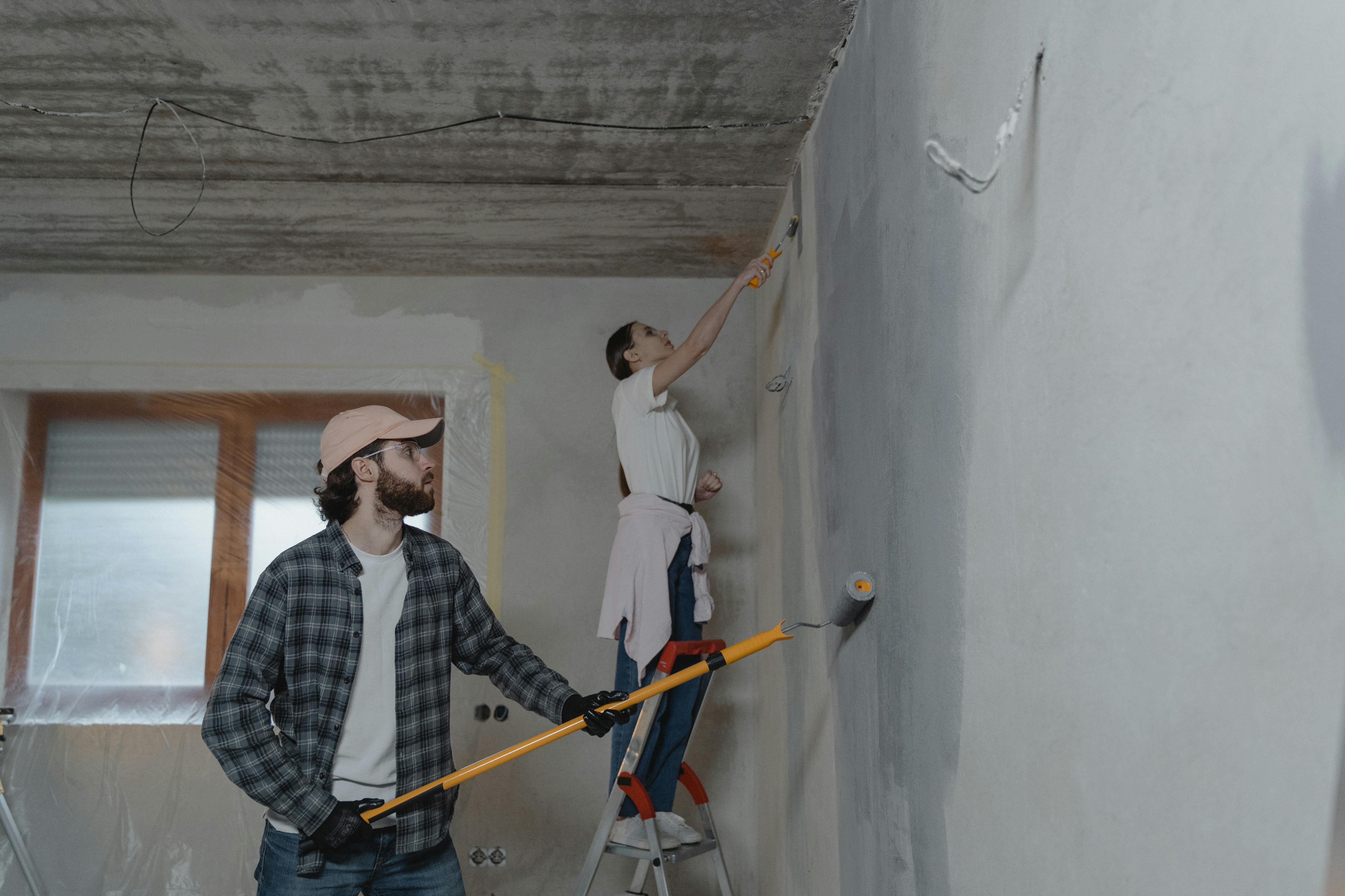 A couple painting a room together, highlighting teamwork in home renovation.